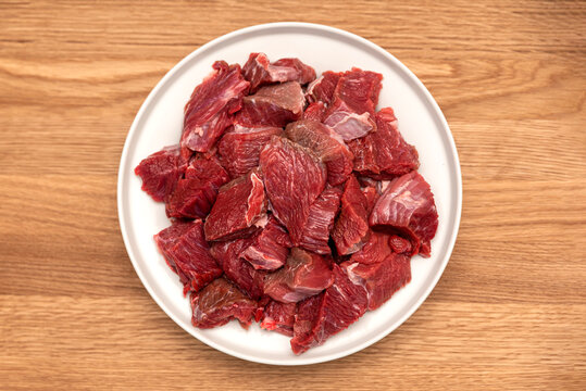 Cooking pilaf in a cauldron, a recipe for real pilaf. Ingredients for cooking pilaf on a wooden background. Raw meat on a wooden cutting board, cut into pieces