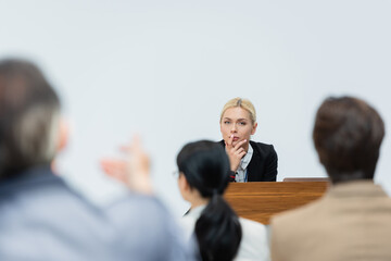 blonde speaker listening to blurred businessman asking question during seminar