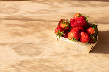 Bowl full of red strawberries on a wooden background on a sunny day.