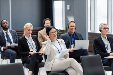 Smiling asian businesswoman in headset holding digital tablet during seminar