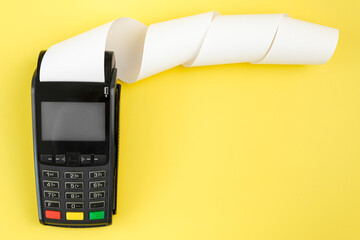 Payment terminal POS with a roll cash tape on the yellow background with copy space