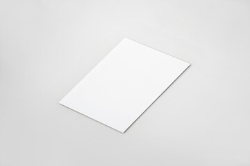 Single vertical blank paper mockup template. Perspective angle on a neutral grey background. 