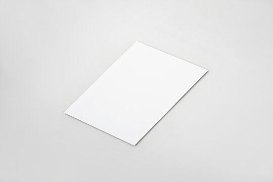 Single Vertical Blank Paper Mockup Template. Perspective Angle On A Neutral Grey Background. 