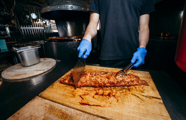 Male butcher or chef is preparing prime rib steaks from a large beef rib roast.