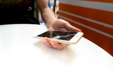 Close up of young asian man sitting on couch, holding smartphone in hands, typing message, posting in social media, chatting with friends or relatives, playing online game, doing purchases.