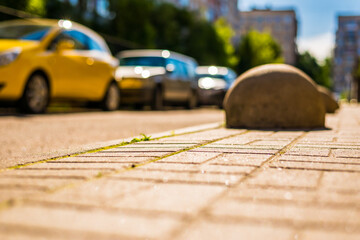 Naklejka premium Sunny day in a city, sidewalk in city courtyard with parked cars. View from the pavement level