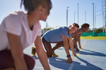 Happy runners at starting line on sunny sports track