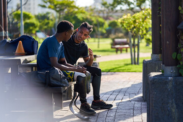Coach and young male amputee athlete talking on park bench