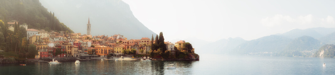Early morning view of the Como Lake with the village of Varenna, Italy, and clear sky, with fog,...
