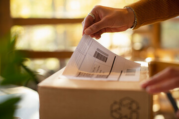 Close up business owner placing shipping label on package