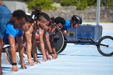 Wheelchair athlete at starting line with sprinters on sunny track