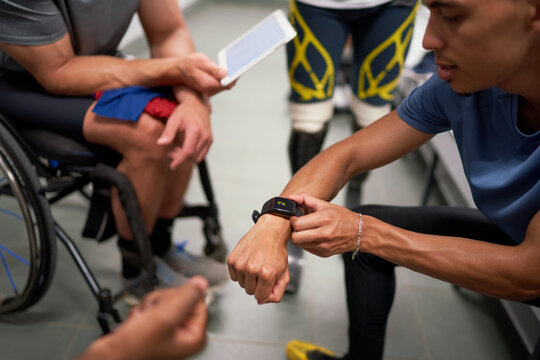 Male amputee and wheelchair athletes with smart phone in locker room - Powered by Adobe