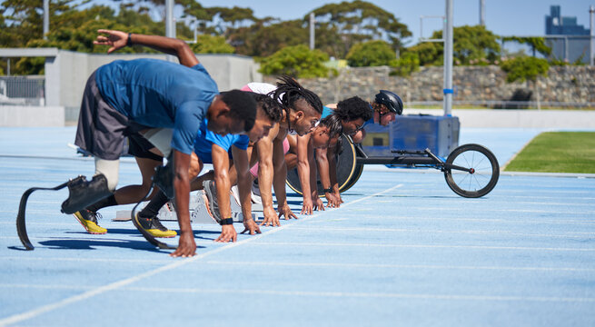 Diverse athletes ready at starting line on sunny blue sports track