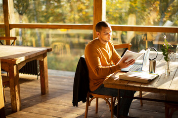 Businessman with paperwork working in sunny autumn cafe
