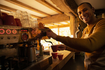 Portrait happy male barista preparing coffee at cafe espresso machine
