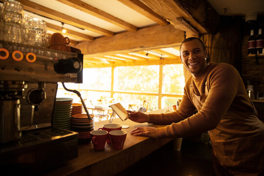 Portrait happy male coffee shop owner working behind counter - Powered by Adobe