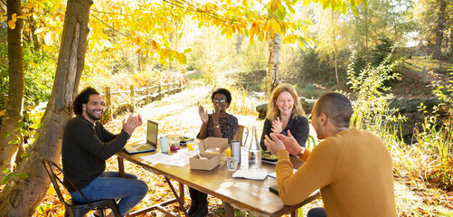 Happy business people clapping and meeting in sunny autumn park