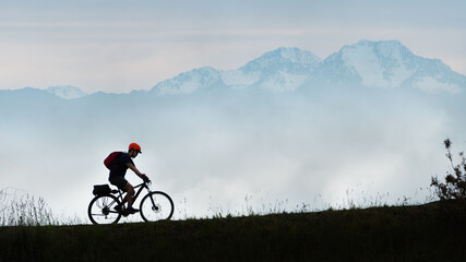 A cyclist riding uphill with misty mountains in the background, South Island of New Zealand