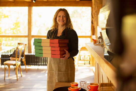 Portrait happy female pizzeria owner holding pizza boxes