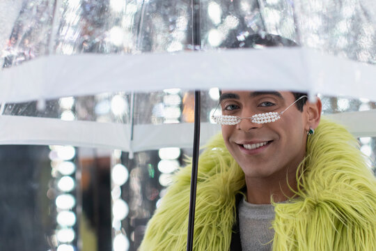 Portrait Stylish Young Man In Feather Boa Under Umbrella