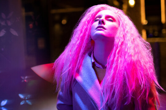 Beautiful woman with pink hair and head back under light