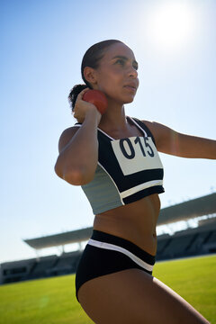 Focused female track and field athlete throwing shot put