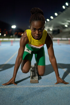 Portrait focused female track and field athlete at starting block