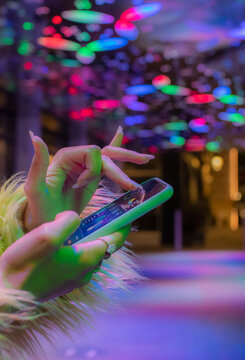 Close up woman using smart phone in nightclub under neon lights