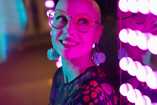 Close up portrait beautiful woman with shaved-head, head by neon light