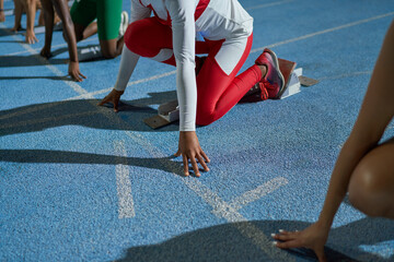 Female track and field athletes at starting line on blue track