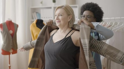 Satisfied customer trying on tailored jacket in fashion clothing studio, trends