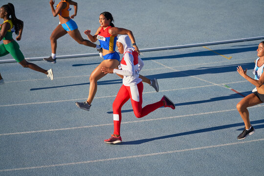 Female track and field athletes running in competition on sunny track