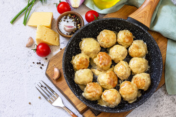 Homemade Meatballs with cheese sauce in a pan on a light stone or slate.