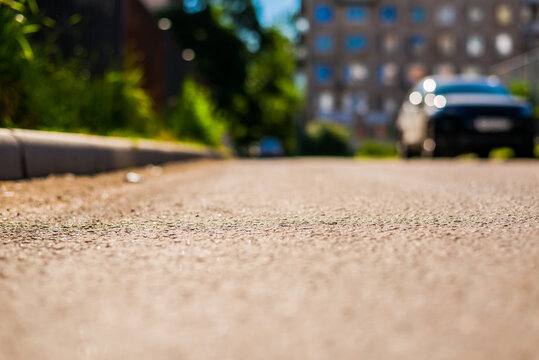 Sunny day in a city, bad road in city courtyard with parked cars. View from the curb level