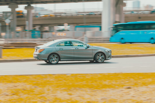 Side view rolling shot with gray car in motion. Mercedes CLA-Class driving along the street in city with blurred background