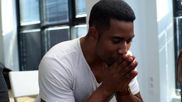 Close-up face of sad African American young man sharing problem sitting in circle on group interpersonal therapy session. Tracking shot of depressed black male talking about psychological problems.