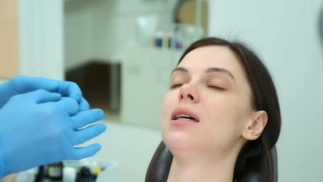 Orthodontist doctor checks the closing of woman teeth with silicone invisible transparent trainer using carbon paper. Portrait of woman in dentistry. Correcting teeth. Oral hygiene, treatment, cure.