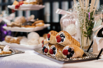 rolls with cream and fresh berries on a sweet table for a holiday