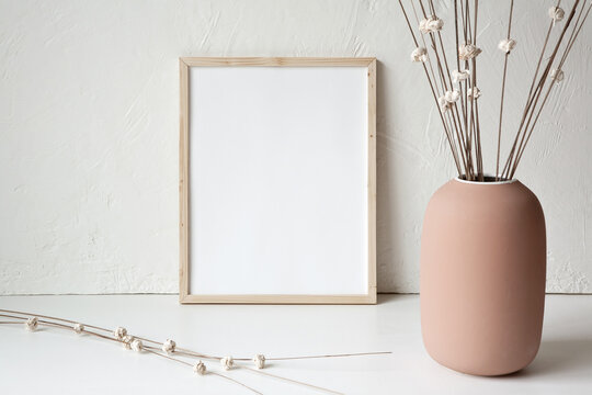11x14 thin wood vertical frame mockup template. Neutral white background. Terracotta vase with artificial dried flowers.