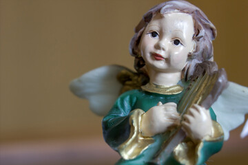 Fototapeta premium Extreme close up macro of an angel with wings playing an instrument isolated on plain background.