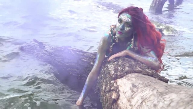 Mermaid lies on the tree around the water slow motion