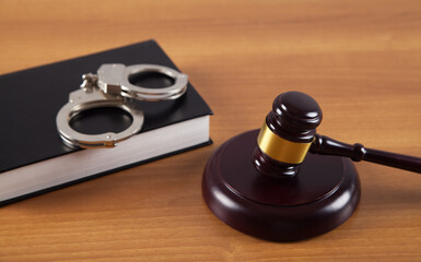 Gavel and handcuffs legal book on wooden table.