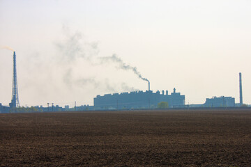 Industrial landscape. Silhouette of a factory with chimneys against a gloomy gray sky