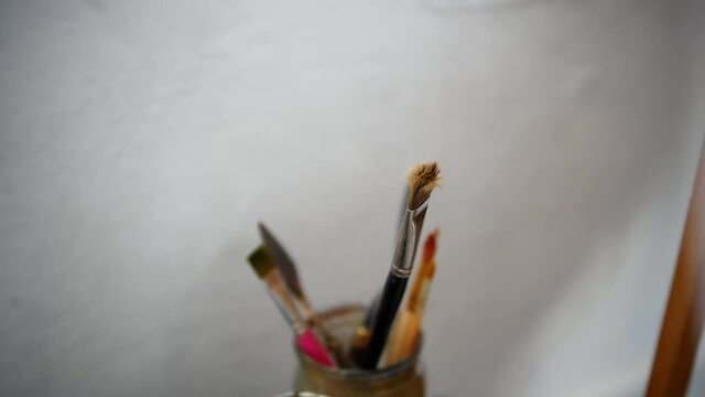 Close-up macro shot of video. Artist's brush for painting with oils or acrylics on a blank canvas in an art workshop.