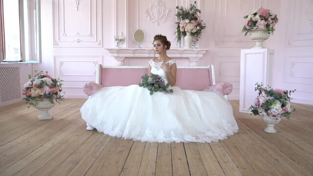 A Girl In A Beautiful White Dress Sits On The Bed And Looks Away