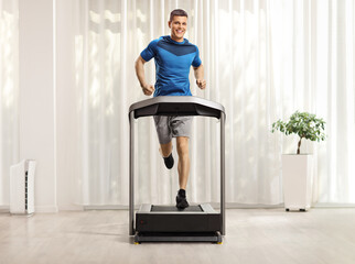 Young man running on a treadmill at home
