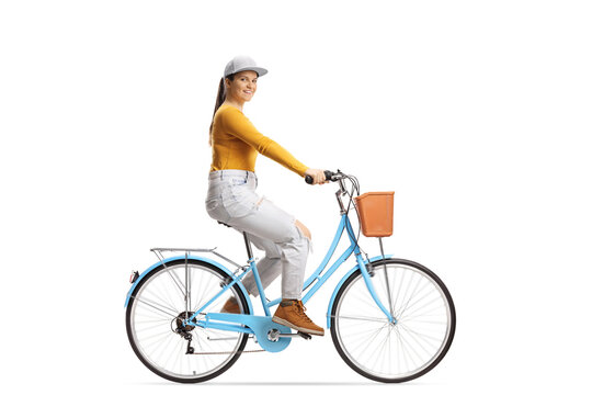 Full length profile shot of a young female riding a city bicycle and looking at camera