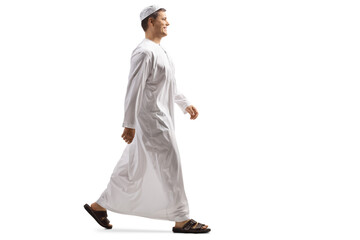 Full length profile shot of a young muslim man in white dishdasha walking - obrazy, fototapety, plakaty