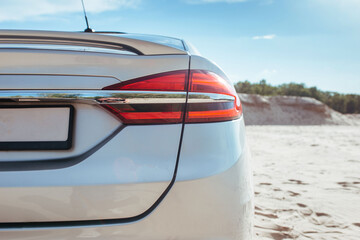 taillight of a gray passenger car standing on the sand