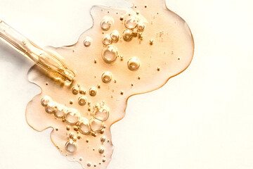 Yellow texture of a drop of whey or olive oil on a white background. Transparent sample of cosmetic gel with bubbles. Golden acid cream. Vitamin c. A drop of honey. Hyaluronic acid.